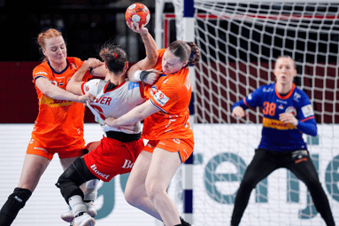 De handbalvrouwen doen er alles aan om een doelpunt te voorkomen
